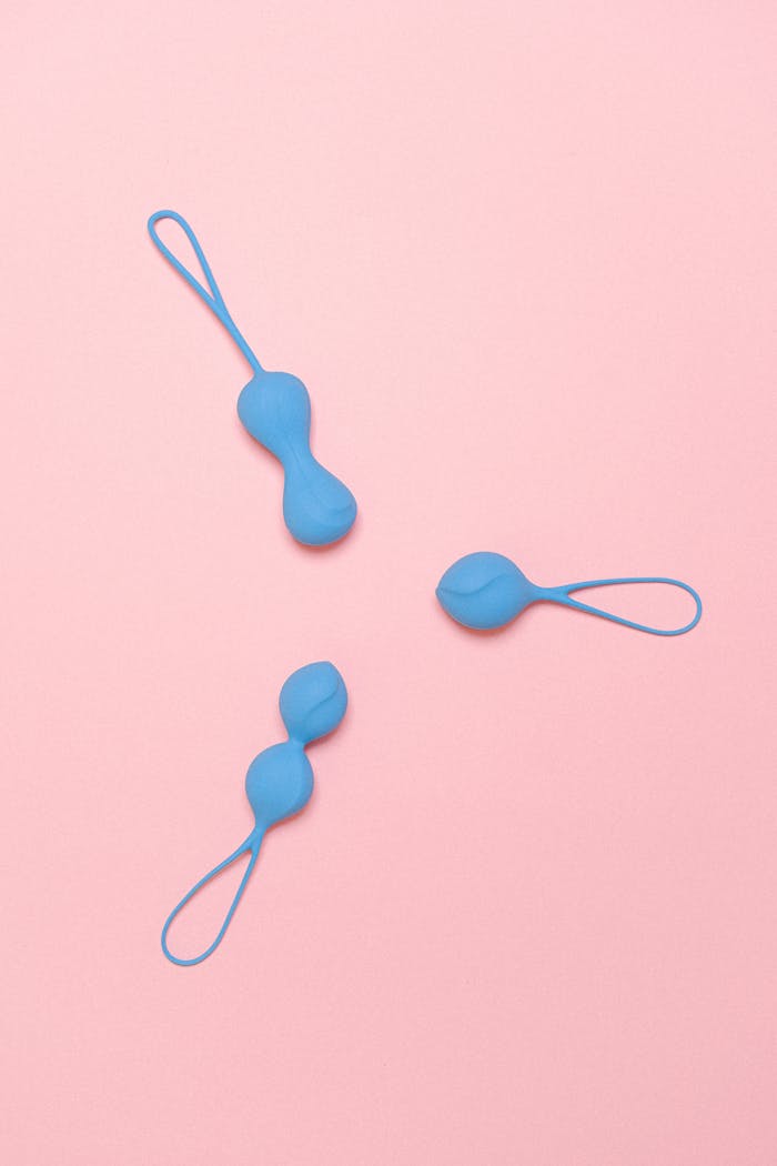hero-img-01 Three blue silicone geisha balls arranged on a pink background, top view.